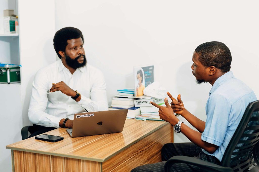 two nigerian men talking in office talking