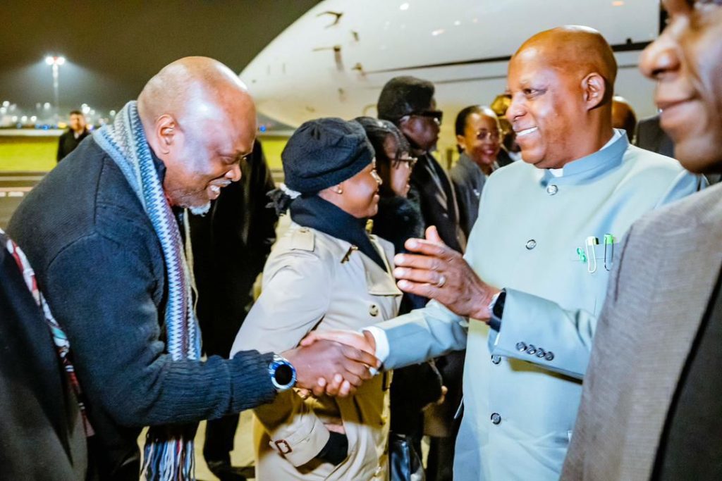 african man greets another travelling african man with handshake at airport