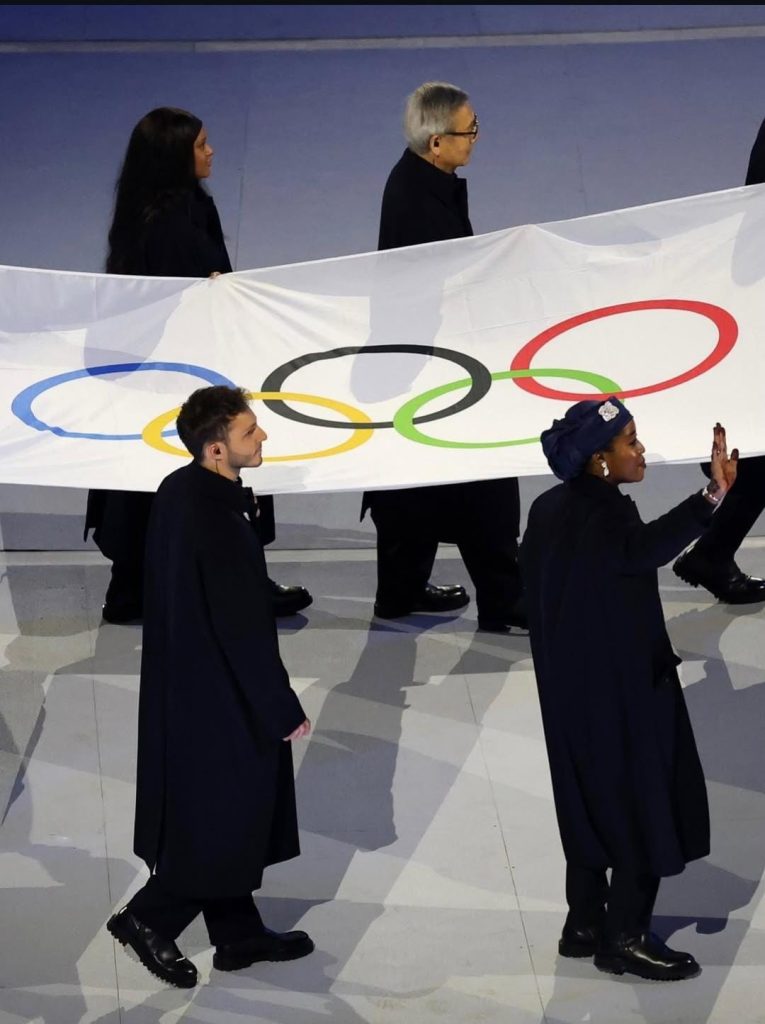 group of people carrying the olynpic flag