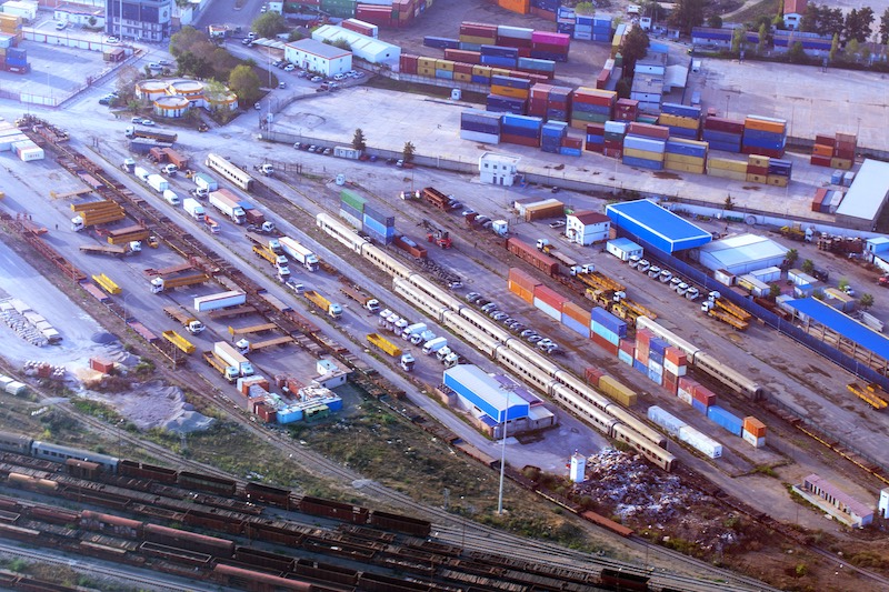 Aerial view of a busy African logistics terminal with cargo trucks, rail tracks, and shipping containers representing regional trade hubs