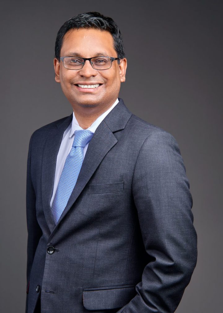 Headshot of Ambrish Maharahaje, Group CEO of Cim Finance in Mauritius, wearing a dark gray suit and blue tie.