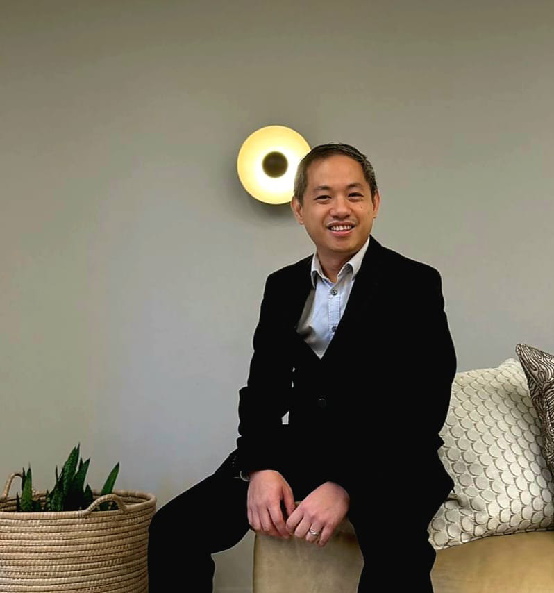 Christopher Pang, Country Head of Alter Domus Mauritius, sitting on a modern office couch in a professional suit, smiling.