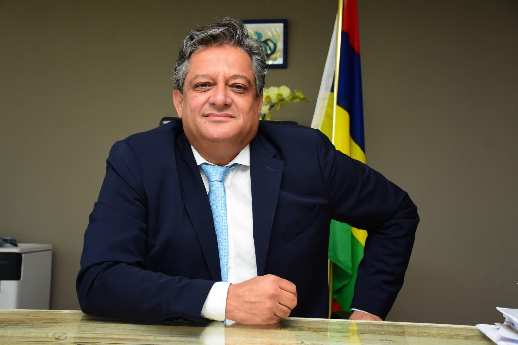 Portrait of Hon. Richard Duval, Minister of Tourism for Mauritius, in a professional suit and blue tie.